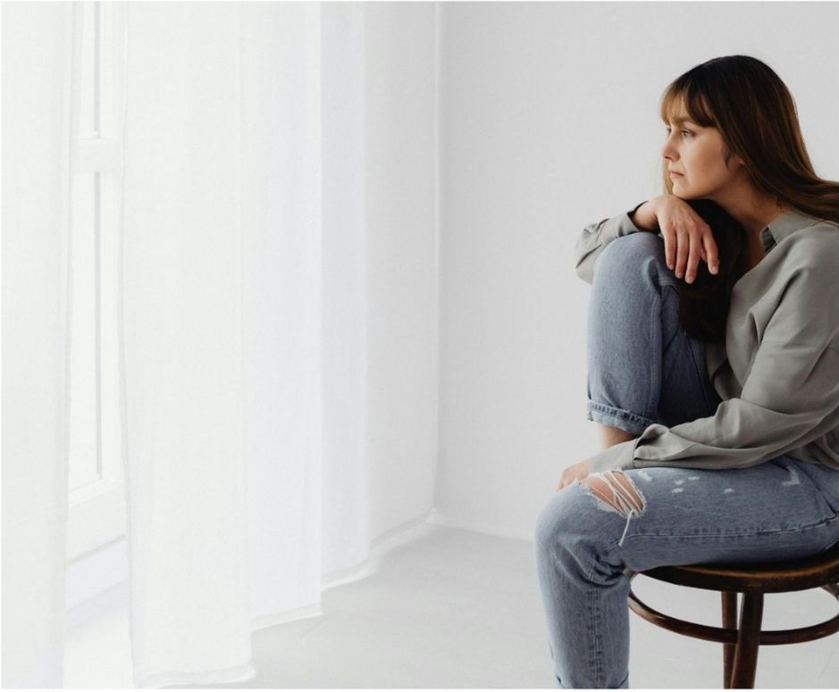 Woman sleeping in bed wearing a smartwatch, sunlight casting stripes on white sheets. Peaceful mood with a cozy, minimalist setting.