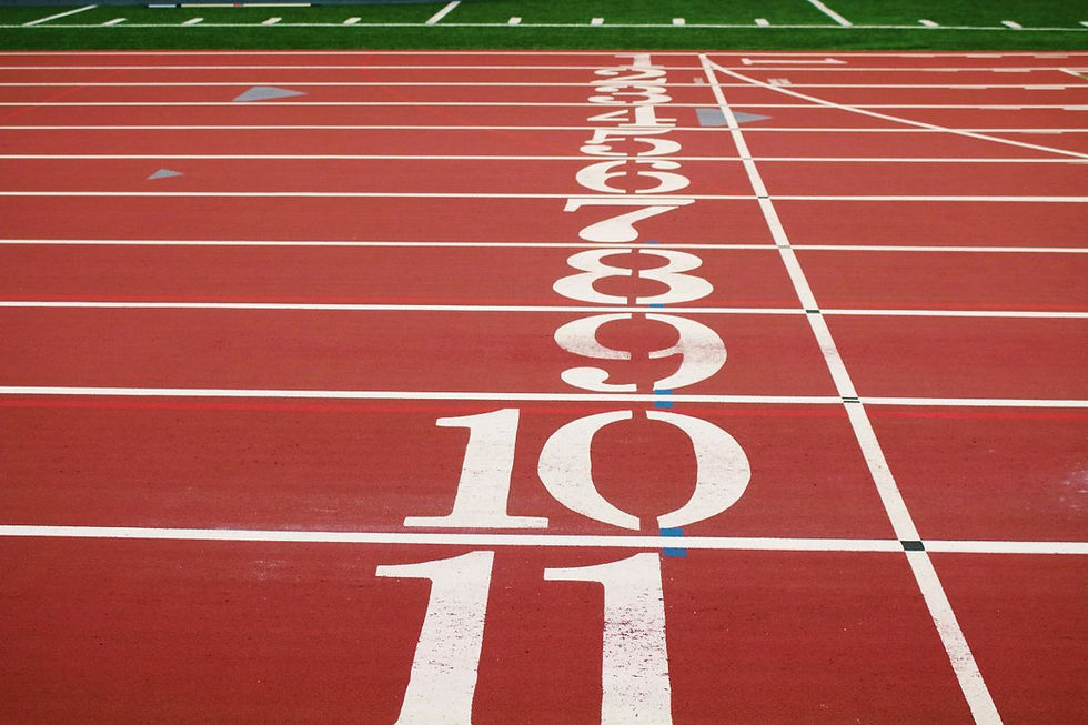 Red running track with white lane numbers 1-11. Green turf visible in the background. No people present. Calm, organized scene.