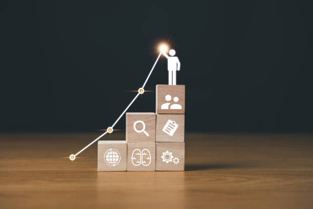 Stacked wooden blocks with icons showing growth. A stick figure reaches the top by a climbing line graph. Simple, professional setting.