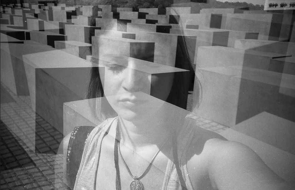 Black-and-white selfie of a serious woman reflected over a maze of concrete blocks, creating a layered abstract scene.