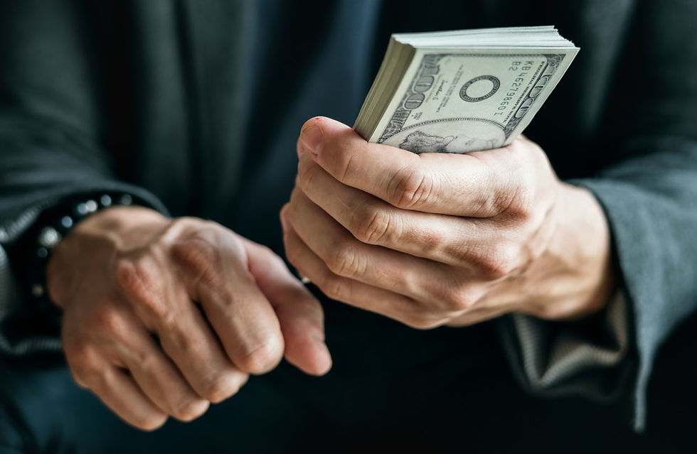Hands in a dark suit holding a thick stack of U.S. dollar bills, suggesting a cash exchange
