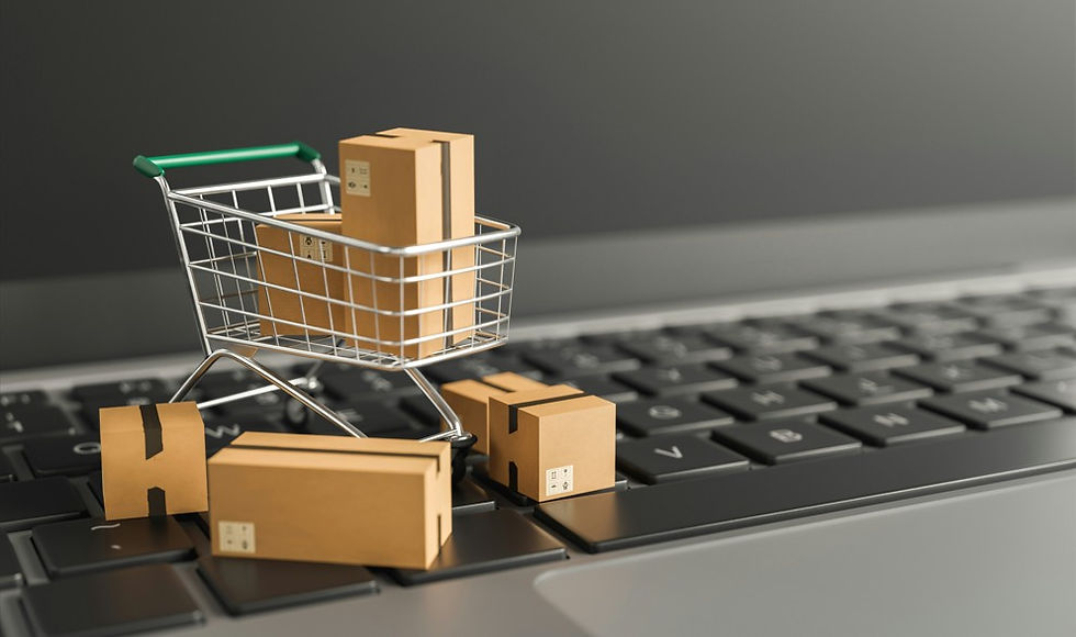 Mini shopping cart filled with cardboard boxes on a laptop keyboard, symbolizing online shopping or delivery.