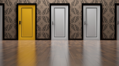 The photo shows a row of doors, with one bright yellow door standing out among several plain grey ones.