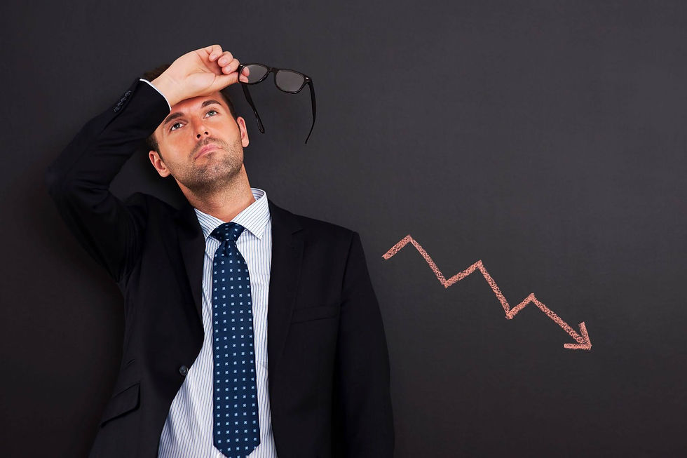 Businessman in suit lifts glasses, looking worried beside a chalk downward arrow on a dark background.