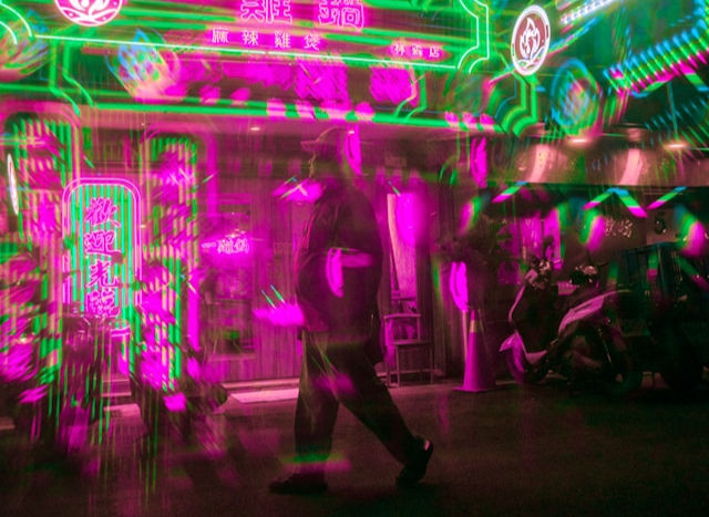 person walking in front of a building with neon lights