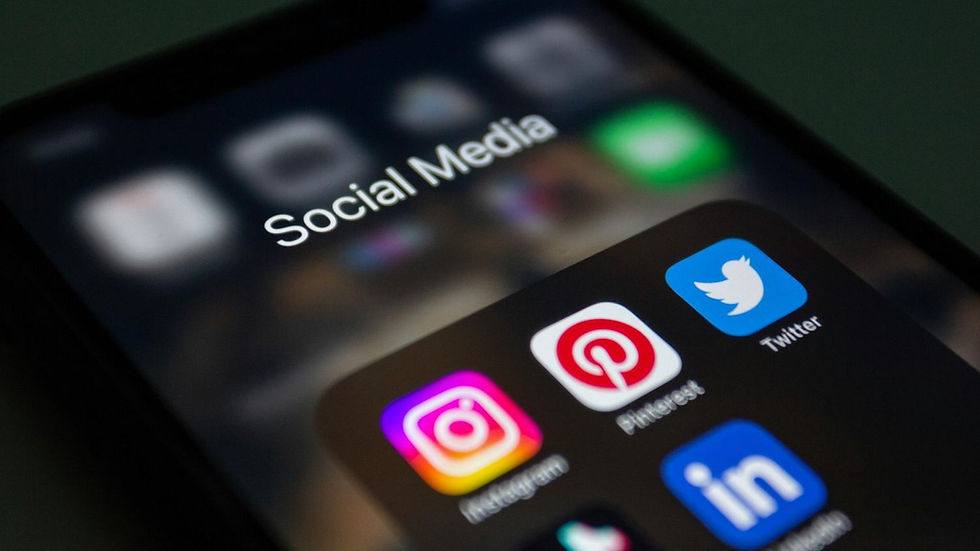 Close-up of a smartphone screen showing social media app icons: Instagram, Pinterest, Twitter, LinkedIn. Text reads "Social Media."