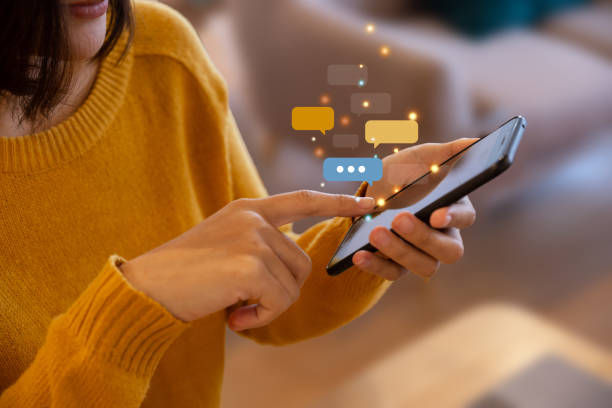 Person in a mustard sweater texting on a smartphone, with illustrated chat bubbles. Cozy indoor setting, conveying a relaxed mood.