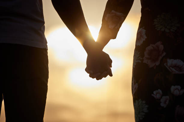 Shot of an unrecognizable couple holding hands while watching the sunset