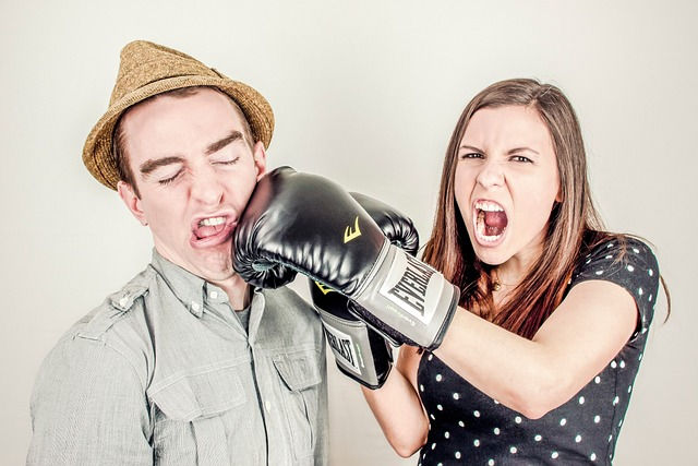 a woman playfully punching a man in the face with a boxing glove