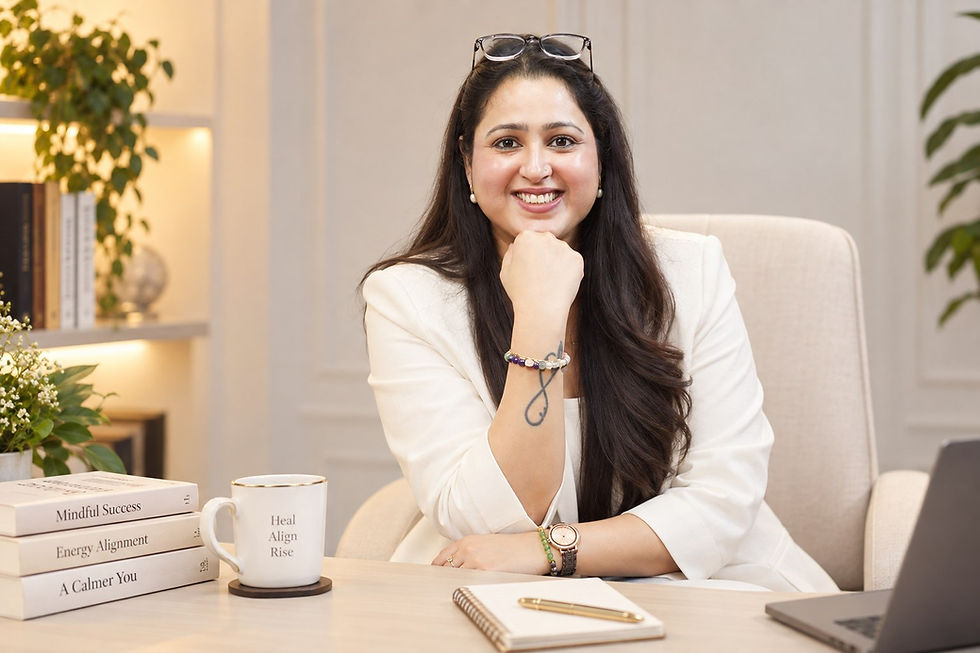 Smiling woman in white blazer at a cozy desk, with books Mindful Success, Energy Alignment, A Calmer You and a Heal Align Rise mug.