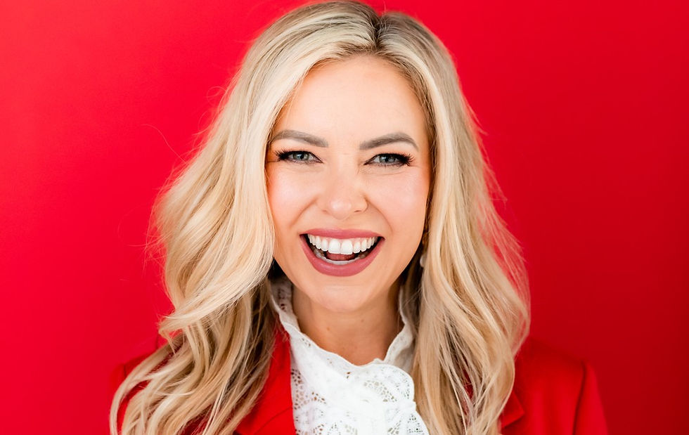 Smiling blonde woman in a red blazer and white lace top against a bright red background, laughing खुशी? No. Need concise English.