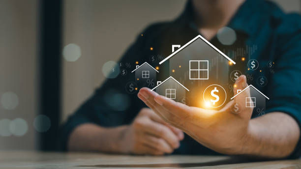 Hand holds glowing house icons with dollar signs, symbolizing real estate investment.