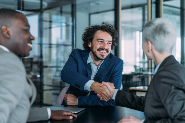 Businesspeople handshaking across the table during a meeting in modern office.