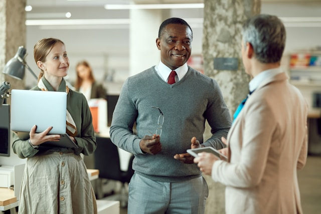 Happy businessman talking to business team at the office