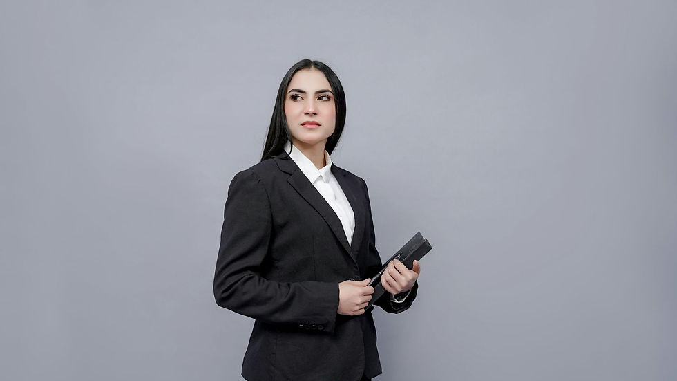 Professional woman in black suit holding a book against a gray background, looking off to the side with a confident expression.