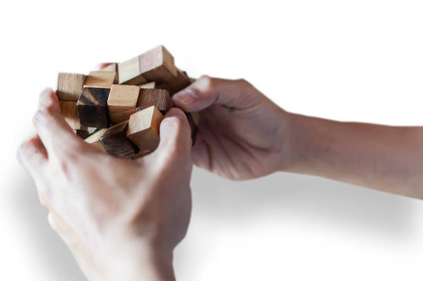 Hands holding a complex wooden puzzle against a white background, showcasing focus and concentration on solving the intricate structure.