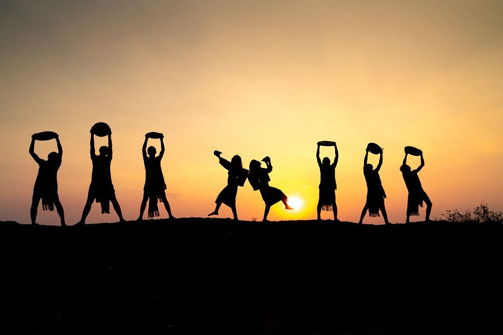 Silhouetted dancers hold objects aloft against a vibrant sunset, creating a lively and joyful scene.