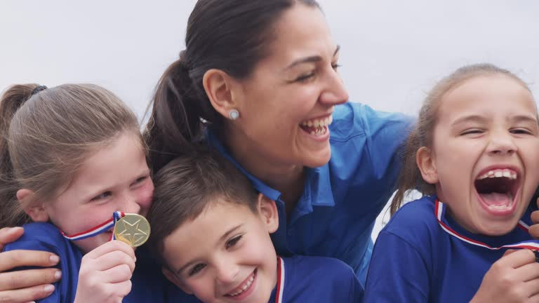 Portrait of children with female coach showing off medals won