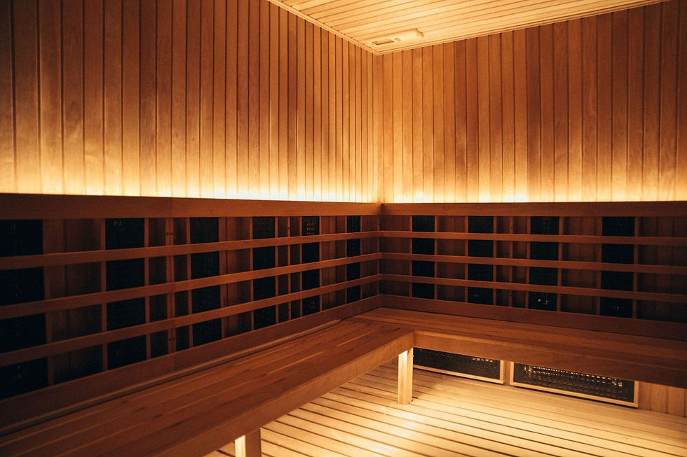 The image shows a warmly lit infrared sauna with wooden walls and benches, creating a cozy and relaxing atmosphere.