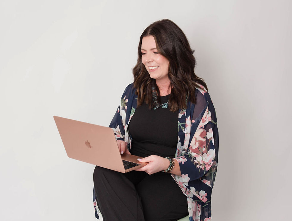 Smiling woman with a floral shawl using a laptop against a plain background. She exudes a cheerful, focused vibe.