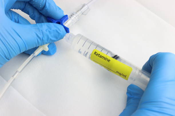 Professional wearing gloves injecting ketamine in a intravenous set with a a 3-way.