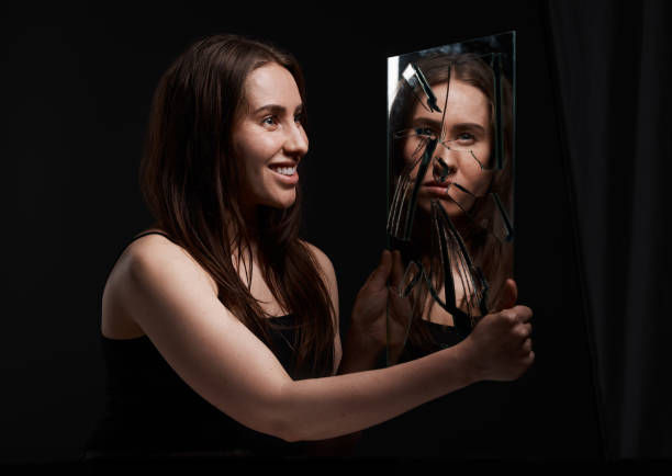 Shot of a woman grinning at her reflection in a broken mirror