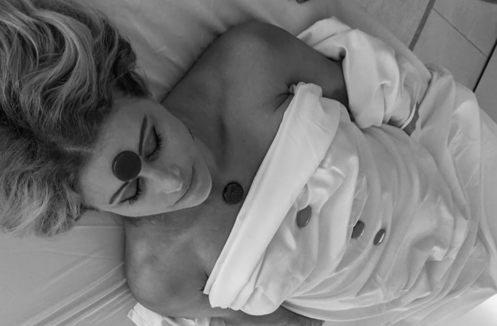 Relaxed woman receiving a holistic healing session with chakra stones placed on her body