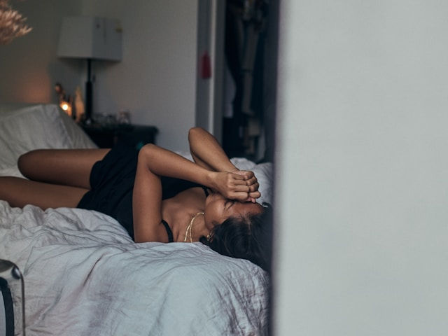 A depress woman in black dress laying in bed