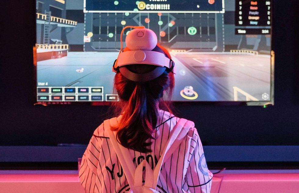Girl in striped shirt wearing VR headset, facing a colorful gaming screen with text "COIN" and player colors. Dark backdrop.
