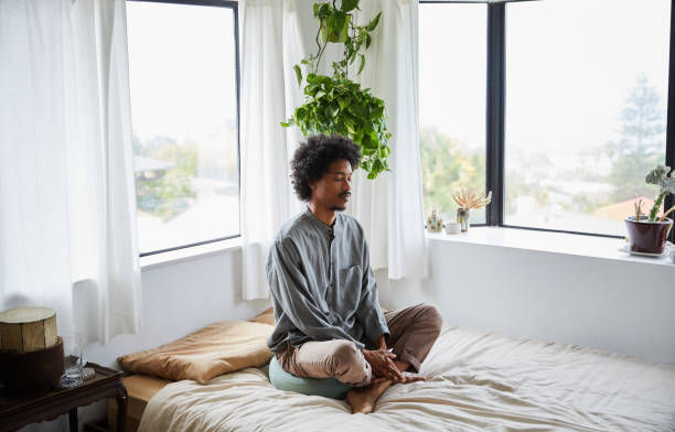 Young man sitting alone on his bed and meditating