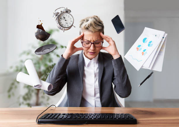 Stressed person at desk with levitating items: clock, phone, cup, papers. Neutral background, business attire. Emphasizes chaos.