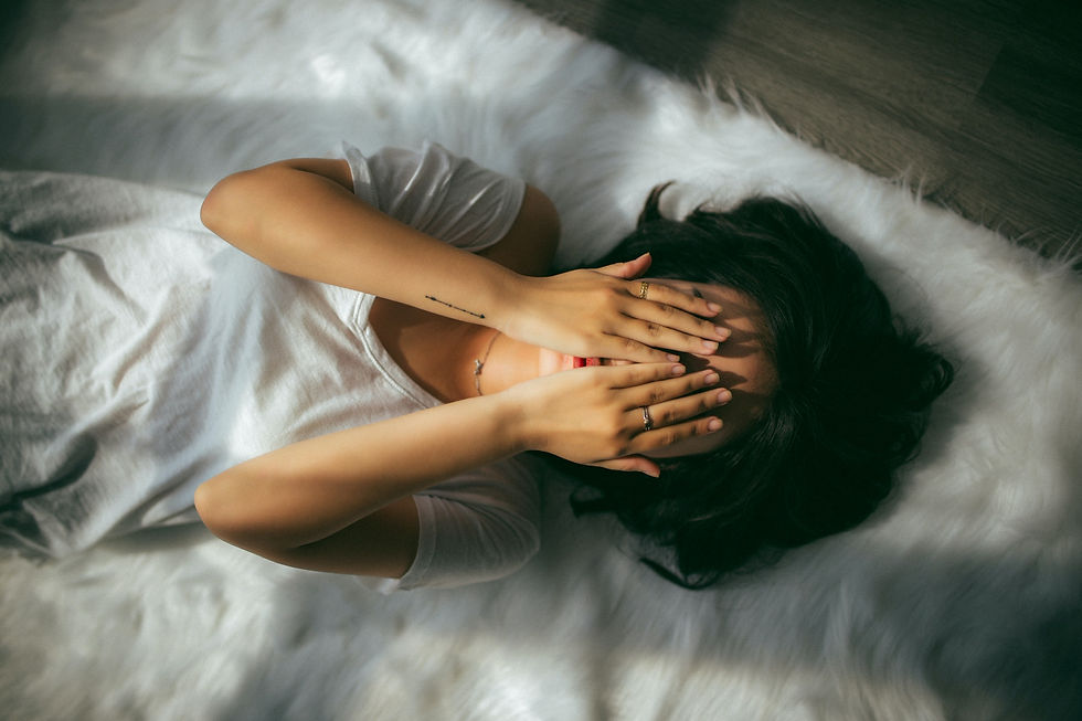 woman in white shirt lying on carpet covering her eyes