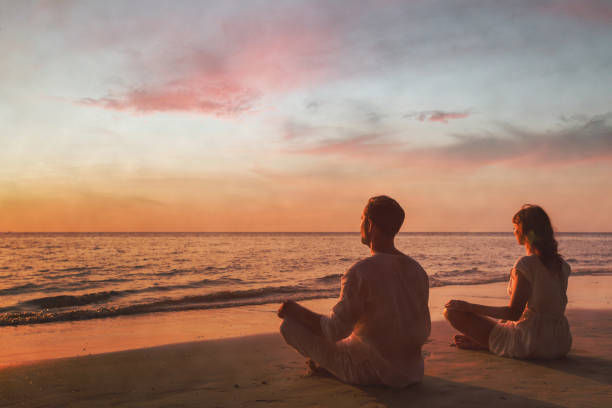 couple doing yoga and breathing exercises at sunset