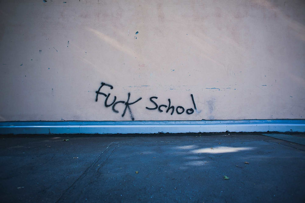 Graffiti on a beige wall reads "F*** school!" in black spray paint. The ground is dark and shadowed, conveying a rebellious mood.