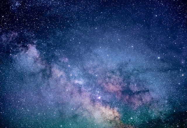 Star-filled night sky with vivid hues of blue, purple, and pink, depicting a view of the Milky Way galaxy. Majestic and serene atmosphere.
