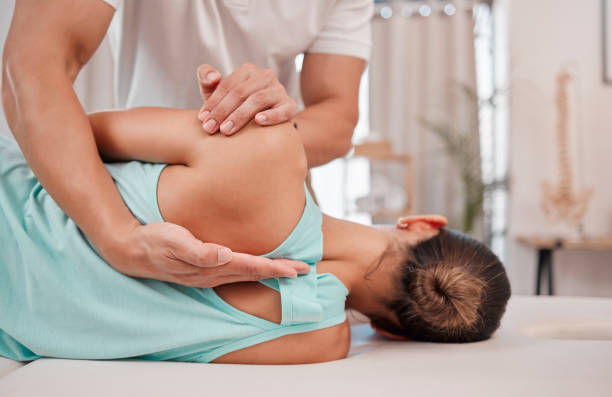 Therapist adjusting a woman’s back and hip on a treatment table in a bright clinic, suggesting calm care and relief