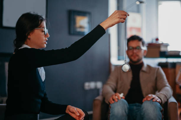 A photo of a young businessman, stylishly dressed wearing a plaid cream suit, jeans, and a turtleneck, sitting at the apartment of his hypnotherapist.