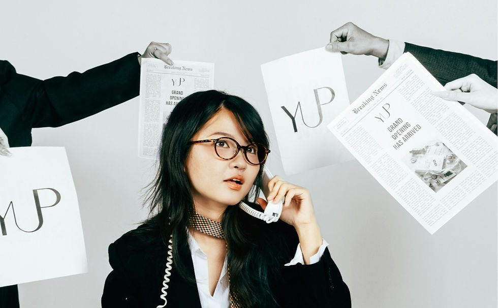 Woman with glasses on phone, surrounded by hands holding newspapers with "YUP" and "Grand Opening Has Arrived" text. Busy office vibe.
