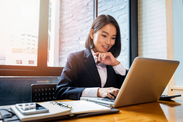 A photo of businesswoman using laptop at office desk.