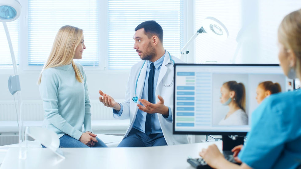A doctor is having a consultation with a female patient while another medical professional reviews facial images on a computer screen.