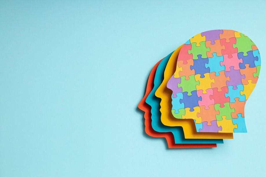 Layered colorful head silhouettes with puzzle pattern on light blue background, symbolizing mind and identity.
