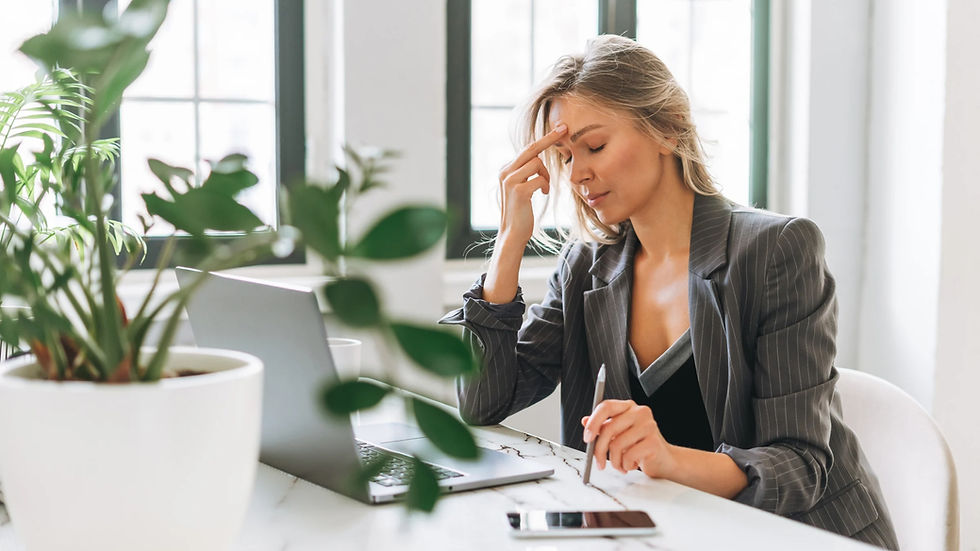 Businesswoman touching her forehead while working in front of laptop