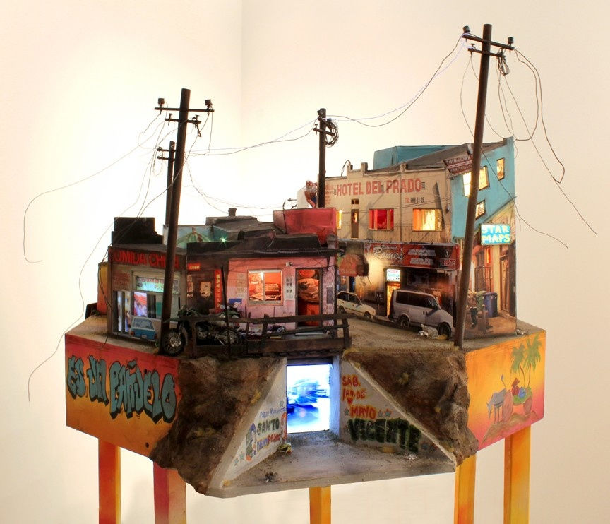 Diorama of an urban scene with colorful buildings, power lines, neon signs, and graffiti. A lit tunnel shows blue light. Mood is lively.