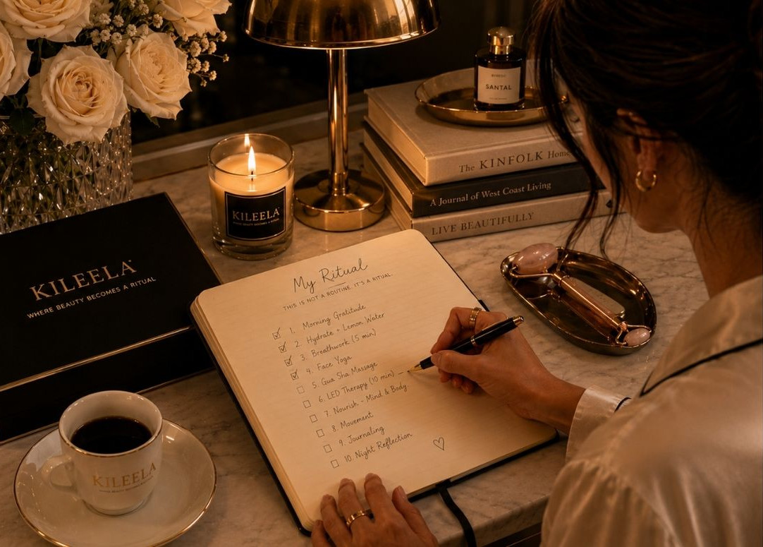 Luxury still life with BYREDO perfume, white roses, gold jewelry, and Kinfolk book on a marble table.