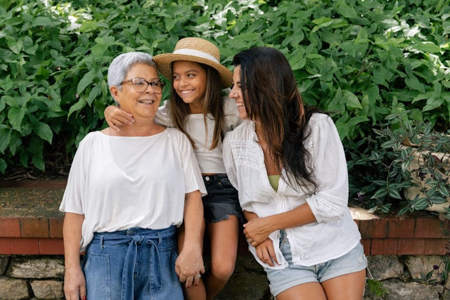 A young girl, her mother, and her grandmother share a joyful moment outdoors