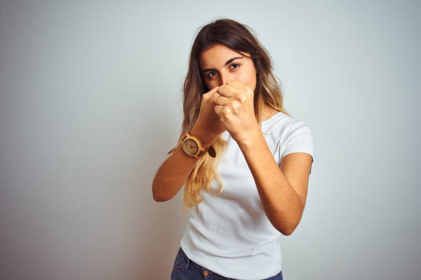 Young beautiful woman wearing casual white t-shirt over isolated background ready to fight with fist defense gesture