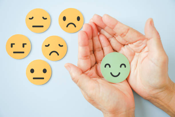 Hand holding happy smile face paper cut with other on background.