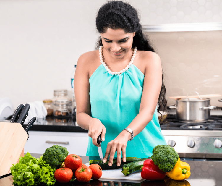 Woman cutting some cucumber in the kitchen.