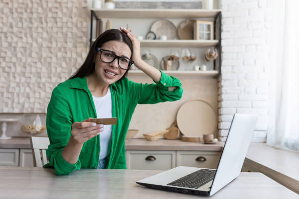 Unsatisfied and disappointed woman at home holding a credit card