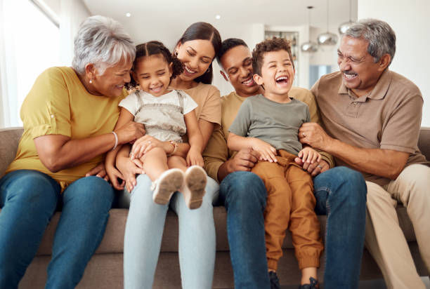 Laughing kids having fun with mom, dad and grandparent on a home living room couch